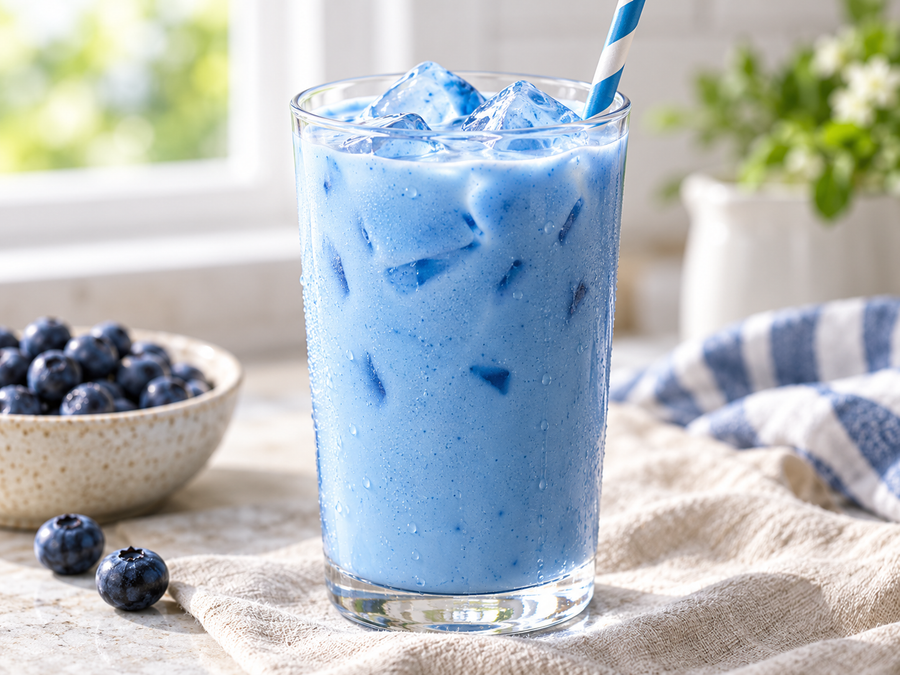 Glass of soft sky-blue spirulina vanilla milk over ice