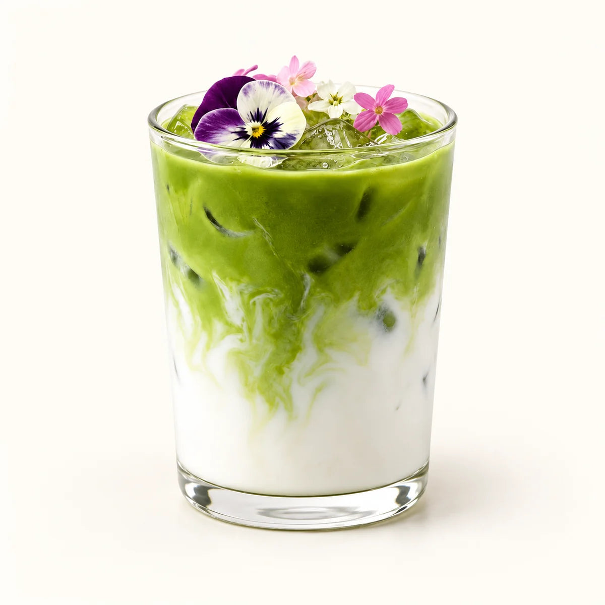 Iced matcha latte in a glass with creamy milk and edible flowers